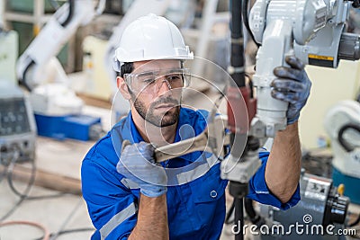 Male engineer using wrench tool repair robot arm welding machine in factory Stock Photo