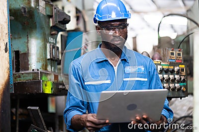 Male Engineer Working on laptop computer in Factory. black male engineer checking Quality control the condition of the machine. Stock Photo