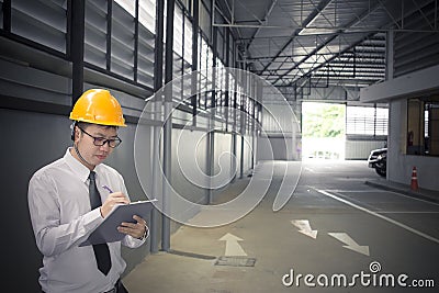 Male engineer writing in factory With note on notepad or industry blurred background Stock Photo