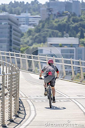 Male enthusiast rides a bicycle on a bike path at Tilikum Crossing Bridge Editorial Stock Photo