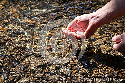 Male european hand refreshing in meditative zen atmosphere in a crystal clear water of a flat little creek with silky ripples Stock Photo