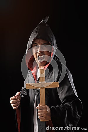 Male exorcist in black coat holding crucifix Stock Photo