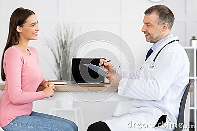 Male experienced doctor talking to his smiling patient Stock Photo