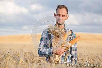 Male farmer or baker with baguettes in rye, wheat field Stock Photo