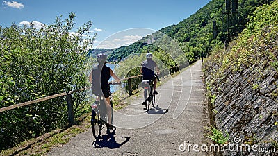 Senior couple cycling along the pretty pathway adjacent to the Rhine River near Koblenz, Germany. Editorial Stock Photo