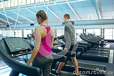 Male and female athletic exercising on treadmill in fitness center Stock Photo