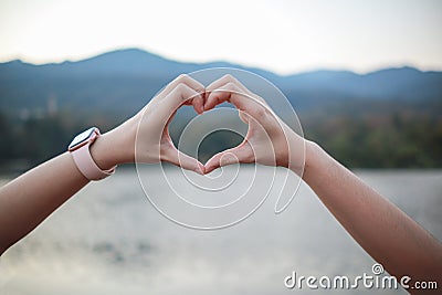 male and female couple showing their hands up to form heart symbol to show friendship love and kindness because heart is symbol of Stock Photo