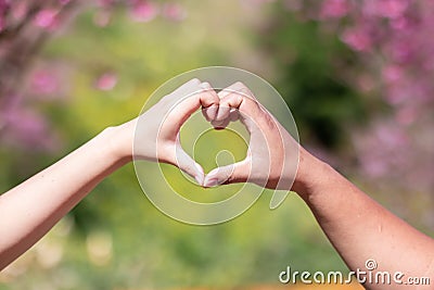 male and female couple showing their hands up to form heart symbol to show friendship love and kindness because heart is symbol of Stock Photo