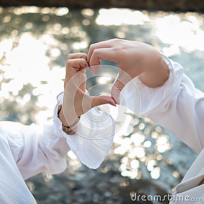 male and female couple showing their hands up to form heart symbol to show friendship love and kindness because heart is symbol of Stock Photo