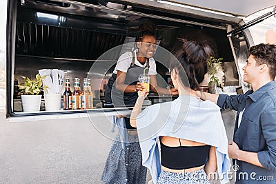 Male and female friends receiving drinks from smiling food truck owner in the city Stock Photo