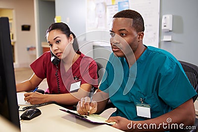 Male And Female Nurse Working At Nurses Station Stock Photo