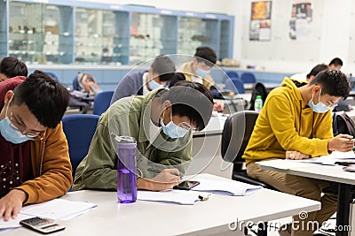 22 01 2021 male and female students doing course or paper work in classroom with face mask in university in Hong Kong during Covid Editorial Stock Photo