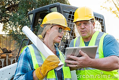 Male and Female Workers With Blueprints and Computer Tablet Stock Photo