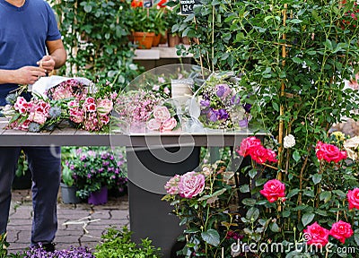 Male florist creating beautiful bouquet in flower shop. outdoor working in flower shop. Man assistant or owner in floral Stock Photo