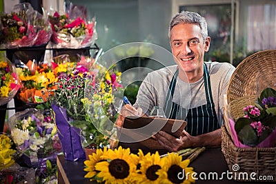 Male florist writing on clipboard Stock Photo