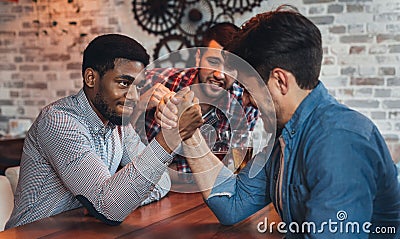 Male friends arm wrestling each other in bar Stock Photo