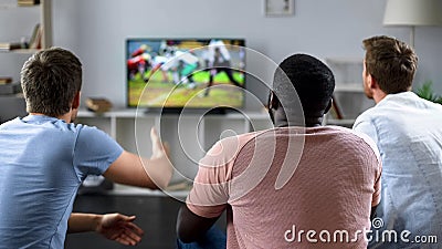 Male friends gather to watch football competition on big screen, sofa experts Stock Photo