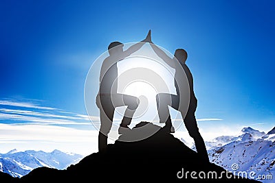 Male Friends Giving High Five On Mountain Peak Stock Photo