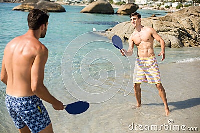 Male friends playing matkot on shore at beach Stock Photo