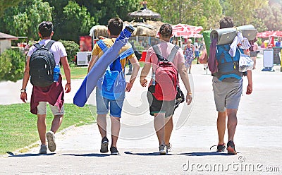 Male friendship concept. Four young guys with travel backpacks go on touristic place. Hike in summer day. Editorial Stock Photo