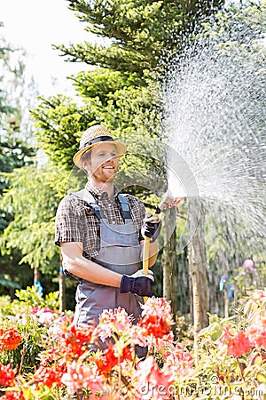 Male gardener watering plants at plant nursery Stock Photo