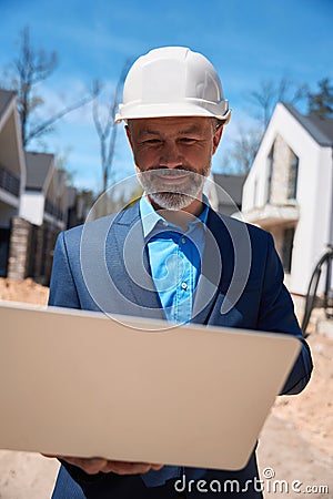Male geodesist checking landscape and lie of ground using laptop Stock Photo