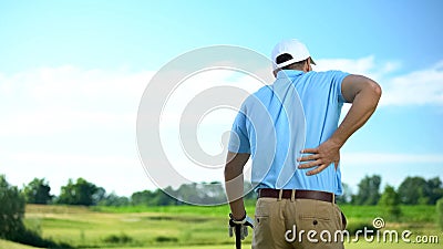 Male golf player feeling strong lower back pain after ball hitting, trauma Stock Photo