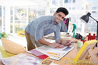 Male graphic designer using mobile phone while working at desk Stock Photo