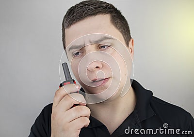 A male guard talking on a walkie talkie with his partner. A policeman takes up the challenge of public safety. Safety and Security Stock Photo