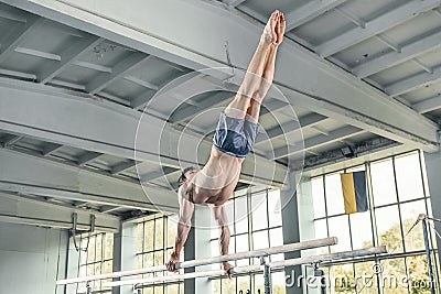 Male gymnast performing handstand on parallel bars Stock Photo