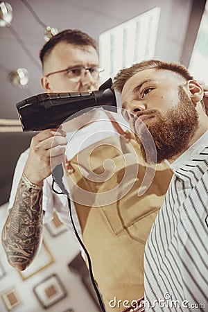 Male hairdresser dries hair of his client Stock Photo