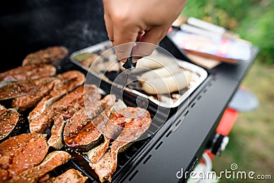 male hand accurate pours sauce on salmon steaks on grill Stock Photo