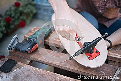Male hand assembling skateboard trucks with screwdriver Stock Photo