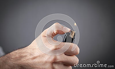 Male hand burning lighter in grey background Stock Photo