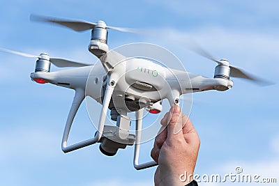 Male hand catches / launches professional drone quad copter DJI Phantom 4 Pro with digital camera 4K on background of autumn blue Editorial Stock Photo