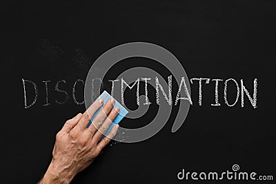 Male hand cleaning word Discrimination on chalkboard Stock Photo