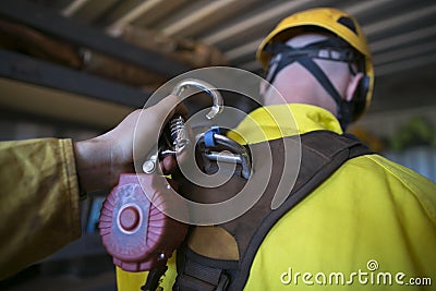 Male hand clipping locking carabiner which connecting with self retracting absorber safety device Stock Photo