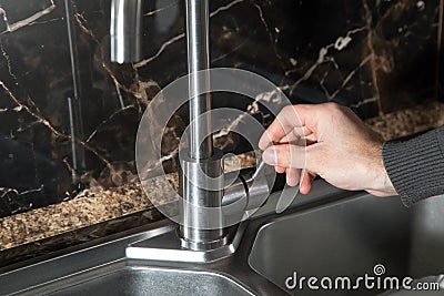 Male hand close kitchen faucet Stock Photo