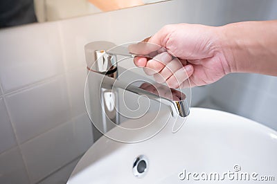 Male hand closing water tap in bathroom Stock Photo