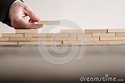 Male hand completing building wall of wooden bricks Stock Photo