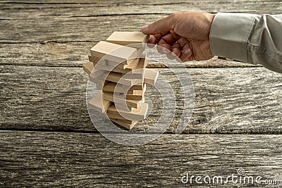 Male hand creating or building a tower of many wooden blocks Stock Photo