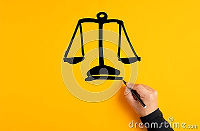 Male hand drawing a justice scale on yellow background. Fairness, equality or trust Stock Photo