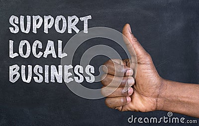 Male hand giving the thumbs up gesture to the phrase Support Local Business Stock Photo