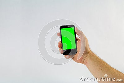 Male hand holding cell phone on white background with green scre Stock Photo