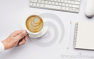 Male hand holding coffee cup latte art on white modern working table Stock Photo