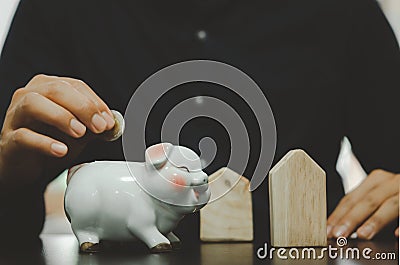 Male hand holding a coin in a white pig piggy bank. Business concepts, finance, savings, taxes and retirement investments Stock Photo