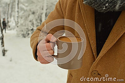 Male hand holding cup of coffee with snowy background Stock Photo