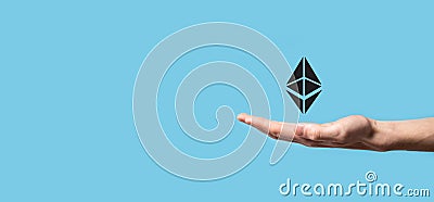 Male hand holding a Ethereum icon on blue background. Ethereum and cryptocurrency investing concept. exchanging, trading, transfer Editorial Stock Photo