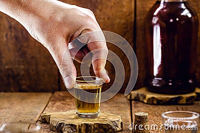 Male hand holding a glass of distilled alcoholic beverage, called Stock Photo