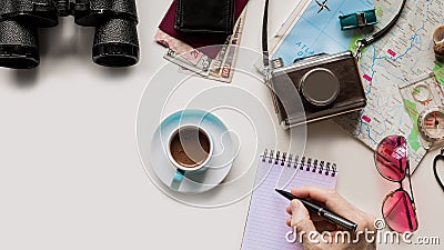 Male hand holding a pen and writing in notebook [inscription] on the table with traveling objects Stock Photo